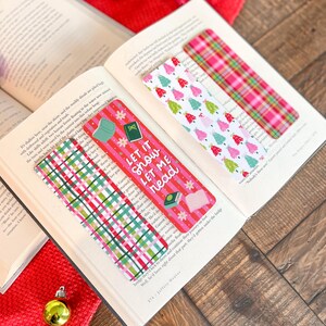 May include: Three Christmas-themed bookmarks with red, green, and white plaid patterns. One bookmark features a white background with pink and green Christmas trees. Another bookmark has a red background with white stripes and the text "Let it snow, let me read".