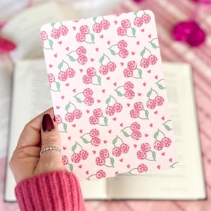 May include: A pink and white card with a repeating pattern of cherries and hearts. The cherries are pink and green and the hearts are pink.