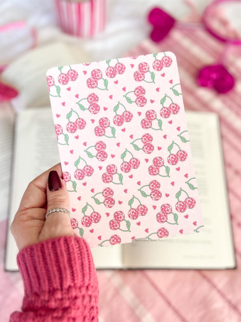 May include: A pink and white card with a repeating pattern of cherries and hearts. The cherries are pink and green and the hearts are pink.
