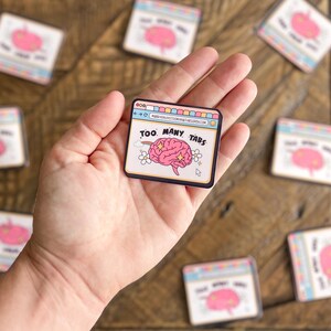 Pu&ograve; includere: Un cervello rosa con stelle all'interno di una finestra del browser con il testo "Too Many Tabs" su una superficie di legno.