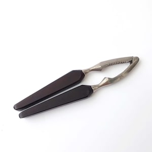 May include: A vintage nutcracker with a dark brown wooden handle and a silver metal cracking mechanism.