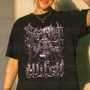 May include: Black t-shirt with a purple and white graphic of a woman and the words "Scarlet Witch" in a gothic style. The design is from "Babylon Prints". The original artist is credited at the bottom of the image.
