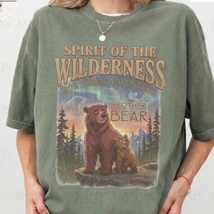 May include: A moss green t-shirt with a graphic of two bears and the text "Spirit of the Wilderness Northern Adventure Brother Bear." The shirt also has the text "Comfort Colors Moss" and "Original Artist of This Design."