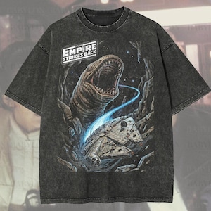 Può includere: T-shirt oversize, lavata al pepe, con grafica da "L'Impero colpisce ancora". Il design include una grande creatura, il Millennium Falcon e il testo "EMPIRE STRIKES BACK". La maglietta è etichettata "Oversized Premium Tee!" e "Original Artist of This Design."