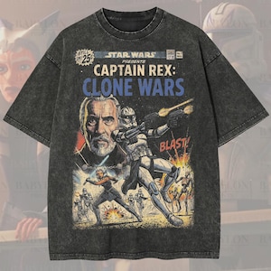 Op de afbeelding: Donkergrijze oversized premium tee met een Star Wars Captain Rex: Clone Wars stripboekontwerp. De afbeelding bevat personages en het woord "BLAST!". Het shirt heeft de tekst "Oversized Premium Tee!" en "Original Artist of This Design".