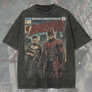 Puede incluir: Camiseta gris oscuro de gran tamaño con una portada de cómic de "Daredevil" y el logotipo de Marvel Comics Group. El gráfico muestra dos personajes en acción. La camiseta también tiene el texto "Oversized Premium Tee!" y "Original Artist of This Design".