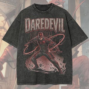 May include: A dark grey oversized t-shirt featuring a Daredevil graphic. The design includes the word "DAREDEVIL" above an illustration of the superhero. The shirt also has the text "Premium Wash: Pepper" and "Oversized Premium Tee!"