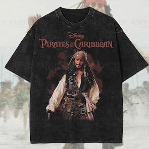 Pode incluir: Camiseta preta oversized premium com um gráfico de Jack Sparrow de Piratas do Caribe da Disney. A camisa tem um efeito de lavagem desgastada. O texto "Disney Pirates of the Caribbean" é vermelho. A camisa também tem o texto "Original Artist of This Design".