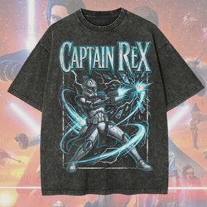 May include: Dark grey oversized t-shirt featuring a graphic of Captain Rex, a Star Wars character, with the text "CAPTAIN REX". The shirt also has the text "Oversized Premium Tee!" and "Original Artist of This Design".