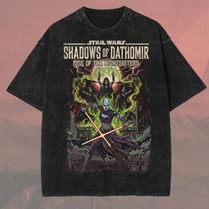 Könnte beinhalten: Schwarzes, übergroßes Premium-T-Shirt mit Star Wars-Grafik. Das Design zeigt den Text "Shadows of Dathomir: Rise of the Nightsisters" und eine farbenfrohe Illustration. Das Shirt hat ein grünes und lila Farbschema und ist mit "Original Artist of This Design" gekennzeichnet.