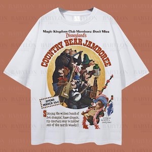 以下が含まれることがあります： ディズニーランドのCountry Bear Jamboreeのヴィンテージスタイルのグラフィックが特徴の白いオーバーサイズのTシャツ。デザインには楽器を演奏するクマと「COUNTRY BEAR JAMBOREE」の文字が含まれています。シャツには「Oversized Tee!」と「Original Artist of This Design」の文字も入っています。