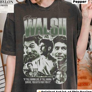 Puede incluir: Camiseta gris oscuro con un gráfico de Shane Walsh y el texto "WALSH" en verde y blanco. La camiseta incluye múltiples imágenes de Shane Walsh y la cita "IF Y'ALL WANNA LIVE, IF Y'ALL WANNA SURVIVE, YOU GOTTA FIGHT FOR IT!"