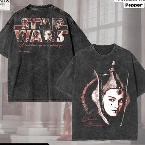 Puede incluir: Camiseta negra de gran tamaño con un diseño descolorido de Star Wars en la espalda y un gráfico de la Reina Amidala en la parte delantera. La parte trasera presenta el logotipo de Star Wars y la frase "Hace mucho tiempo, en una galaxia muy, muy lejana". La camiseta está etiquetada como "Premium Wash: Pepper".