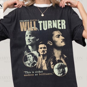 Puede incluir: Camiseta negra con un gráfico de Orlando Bloom como Will Turner. El diseño incluye múltiples imágenes del personaje y el texto "WILL TURNER" y "This is either madness or brilliance."