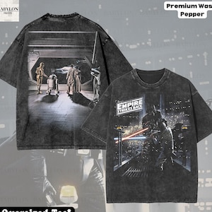 May include: Pepper-washed, oversized tee featuring Star Wars scenes. The front displays Darth Vader in a lightsaber duel, while the back shows C-3PO, R2-D2, and others. The shirt includes the text "EMPIRE STRIKES BACK" and "Original Artist of This Design".