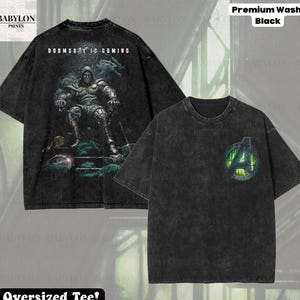 May include: Black oversized tee shirt with a distressed finish. The front features the Avengers logo with a green and yellow design. The back of the shirt has a graphic of a character with the text "DOOMSDAY IS COMING".