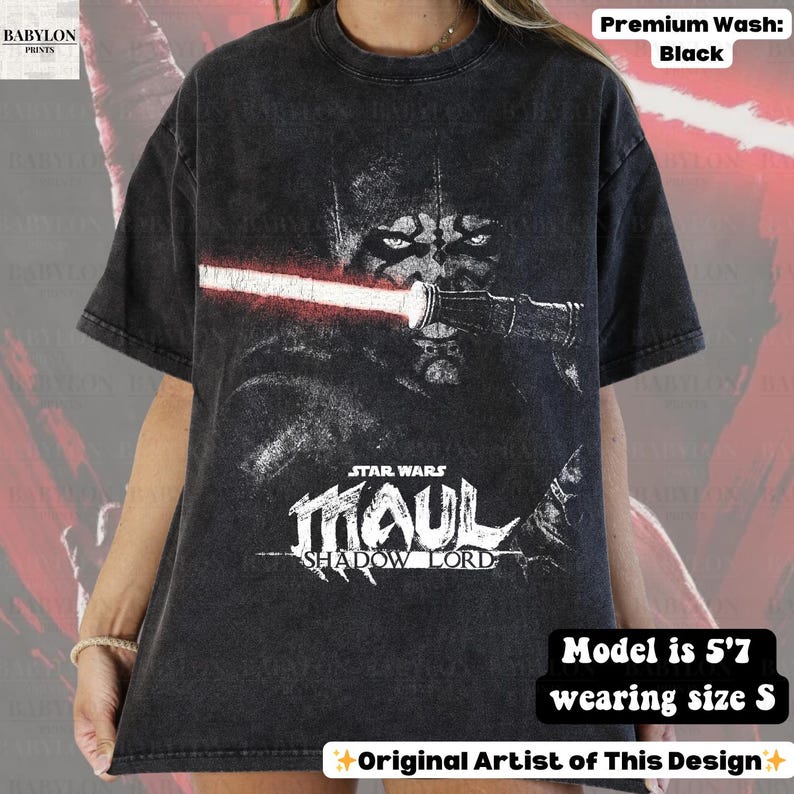 May include: Black t-shirt featuring a graphic of Darth Maul from Star Wars with a red lightsaber. The text "STAR WARS MAUL SHADOW LORD" is below the image. The shirt is a premium wash and the model is 5'7 wearing size S.