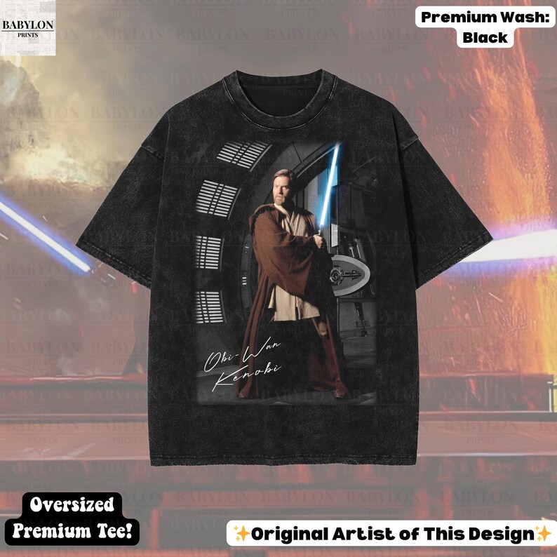 Może przedstawiać: Czarny, duży t-shirt premium z grafiką Obi-Wana Kenobiego trzymającego miecz świetlny. Obraz zawiera tekst "Obi-Wan Kenobi" i "Original Artist of This Design". Koszulka ma pranie premium.