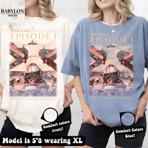 Op de afbeelding: Ivoor en blauwe comfort color T-shirts met een Star Wars Episode I graphic. De graphic bevat de tekst "STAR WARS EPISODE I" en "THE PHANTOM MENACE" met een karakter illustratie. Het model is 173 cm lang en draagt XL.