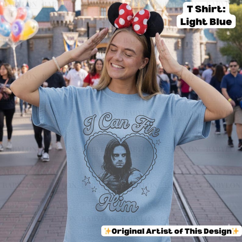 May include: Light blue t-shirt with the text "I Can Fix Him" and a heart-shaped graphic featuring a portrait. The shirt also has small star designs. The text "Original Artist of This Design" is at the bottom.