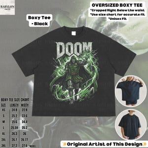 May include: Black boxy tee featuring a graphic of a character with the word "DOOM" in white. The design includes green lightning and a green-clad figure. The shirt has a size chart and the text "Original Artist of This Design".