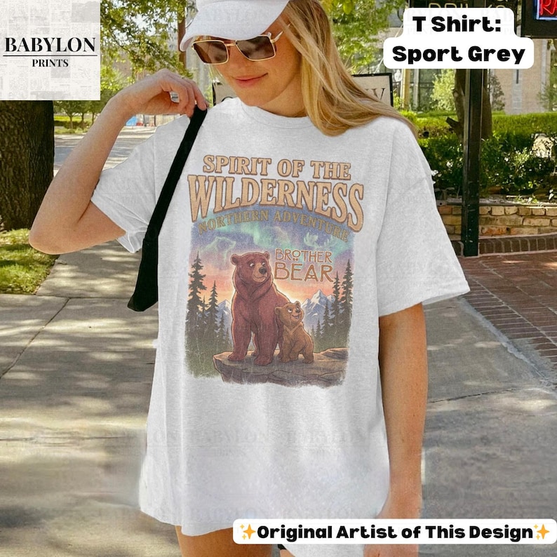 May include: White t-shirt with a graphic of two bears in a forest, the text "SPIRIT OF THE WILDERNESS" and "BROTHER BEAR". The shirt is labelled "T Shirt: Sport Grey" and "Original Artist of This Design".