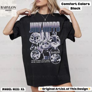 May include: Black t-shirt featuring Judy Hopps from Zootopia. The design includes multiple images of the character and the text "JUDY HOPPS" in a blue gradient. The shirt also has the text "NO MATTER WHAT TYPE OF ANIMAL YOU ARE, CHANGE STARTS WITH YOU."