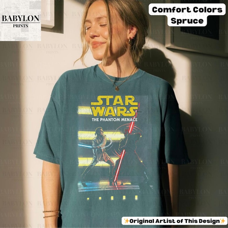 Puede incluir: Camiseta color abeto con un gr&aacute;fico de Star Wars: La Amenaza Fantasma. El dise&ntilde;o incluye el logotipo de Star Wars y personajes con sables de luz. La camiseta es de Babylon Prints y est&aacute; etiquetada como Comfort Colors.