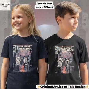 May include: Two youth t-shirts, one navy and one black, each featuring a Star Wars comic book cover design. The graphic includes the text "STAR WARS A NEW HOPE" and illustrations of characters. The shirts are labeled "Youth Tee Navy/Black."