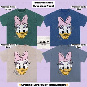 Puede incluir: Cuatro camisetas de gran tama&ntilde;o en colores verde, azul, arena y vaquero, cada una con un gr&aacute;fico de Daisy Duck. Las camisetas tienen un lavado premium y el texto "Premium Wash Oversized Tees!" es visible.