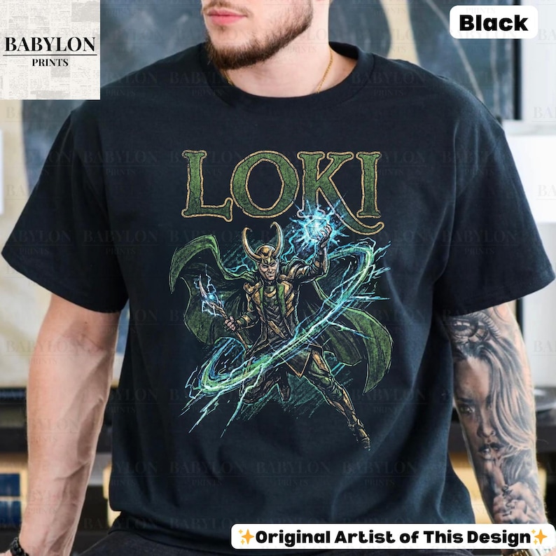 May include: Black t-shirt featuring a green and gold illustration of Loki with the word "LOKI" above. The design includes green lightning and a green cape. The shirt has the text "Original Artist of This Design" at the bottom.
