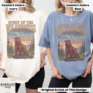May include: Ivory and blue comfort colour t-shirts with a graphic featuring a bear and cub with the text "Spirit of the Wilderness" and "Brother Bear". The design includes a mountain and forest scene.