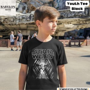 May include: Black youth tee featuring the Star Wars logo and a graphic of a Stormtrooper in a tunnel. The shirt has short sleeves and a crew neck. The text "Youth Tee Black" is in the upper right corner. The Babylon Prints logo is in the upper left corner.
