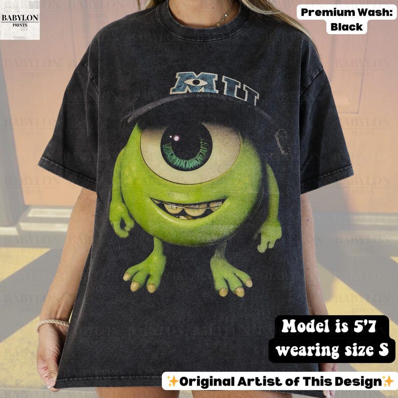 K&ouml;nnte beinhalten: Schwarzes, &uuml;bergro&szlig;es T-Shirt mit einer gro&szlig;en Grafik von Mike Wazowski aus Monsters, Inc., der eine Baseballkappe mit "MIT" tr&auml;gt. Das Shirt ist eine Premium-Waschung und das Model ist 170 cm gro&szlig; und tr&auml;gt Gr&ouml;&szlig;e S. Original Artist of This Design.