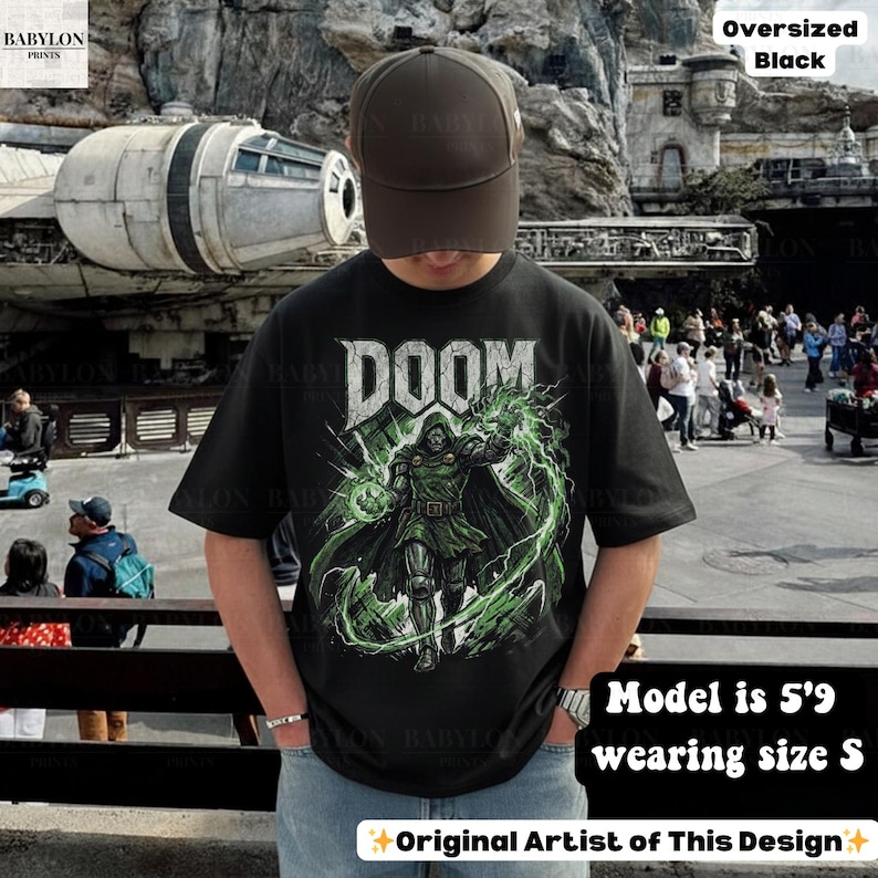 May include: Black oversized t-shirt with a graphic of Doctor Doom and the word "DOOM" in white. The design features green lightning and a green orb. The model is 5'9" and wearing a size S. The shirt is from the original artist.