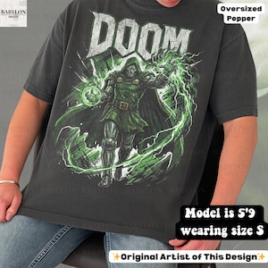 May include: Dark gray oversized t-shirt featuring a graphic of a comic book character with the word "DOOM" in white. The character is in green and black, with green energy effects. The text "Oversized Pepper" is at the top.