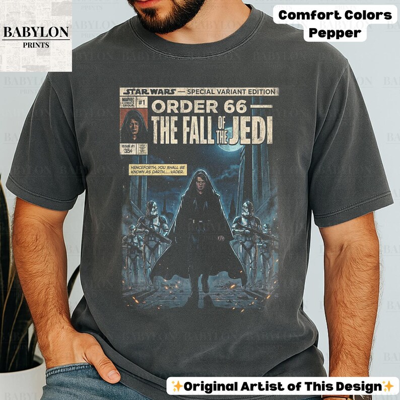 May include: A dark grey t-shirt featuring a Star Wars comic book cover design. The graphic reads "Order 66: The Fall of the Jedi" with Darth Vader and Stormtroopers. The shirt is labeled "Comfort Colors Pepper."
