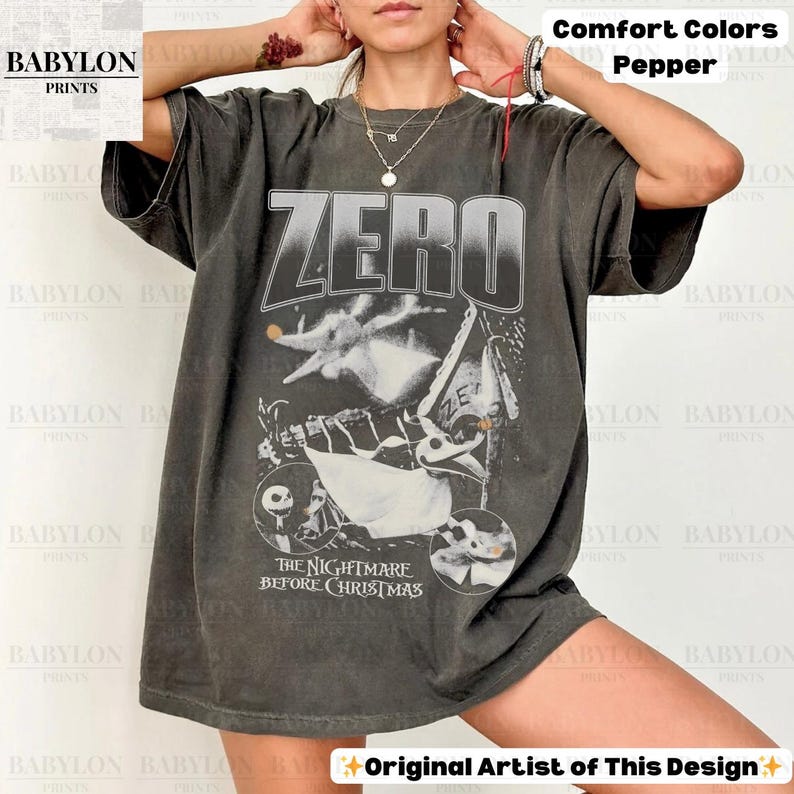 May include: Dark grey t-shirt featuring the word "ZERO" above a graphic from "The Nightmare Before Christmas." The design includes Zero the ghost dog and other characters from the movie. The shirt is a Comfort Colors Pepper tee.
