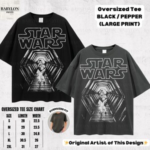 May include: Two oversized black and pepper-colored Star Wars graphic tees. The shirts feature a large print of the Star Wars logo and a tunnel scene. The size chart shows measurements in inches. The text "Original Artist of This Design" is also visible.