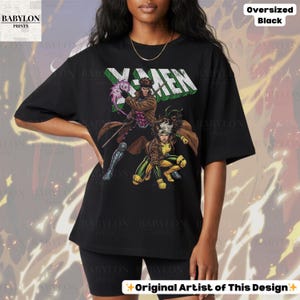 May include: Black oversized t-shirt featuring the X-Men logo and comic book characters Gambit and Rogue. The design includes the text "Original Artist of This Design" and "Oversized Black". The Babylon Prints logo is visible in the upper left corner.