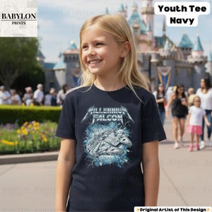 May include: Navy blue youth tee featuring a graphic of the Millennium Falcon spaceship with the text "Millennium Falcon". The design includes lightning bolts and a metallic font. The shirt is labeled "Youth Tee Navy".
