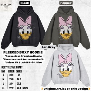 May include: Fleece boxy hoodies in black, pepper, and ash grey, each featuring a Daisy Duck graphic. The hoodies have a pocketless design and are available in sizes S to XL. The size chart indicates lengths from 24.8 to 27.2 inches and widths from 24 to 26.4 inches.