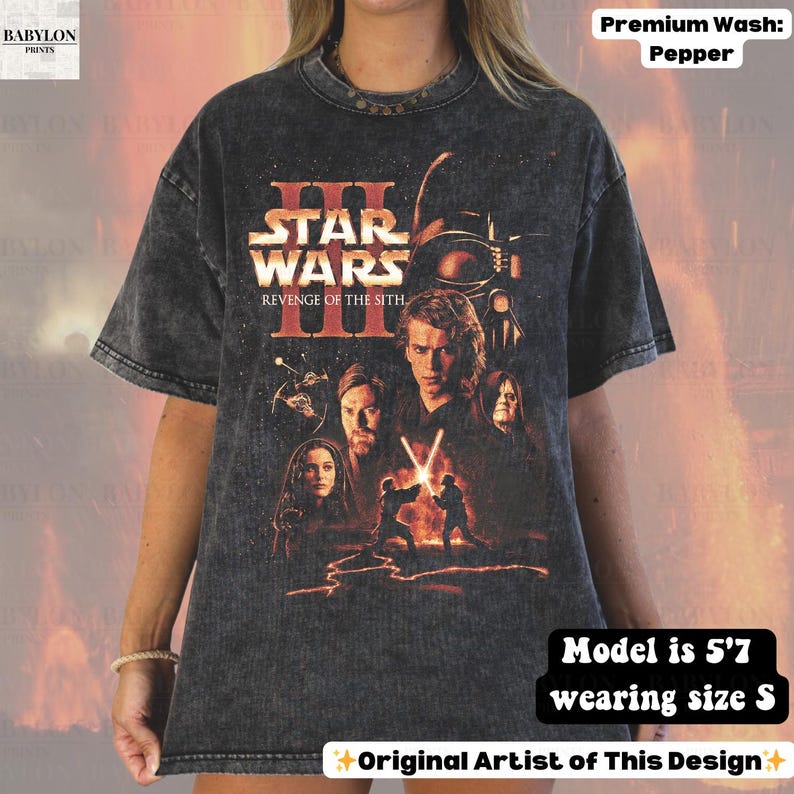 May include: Dark gray t-shirt featuring the Star Wars: Revenge of the Sith movie poster. The shirt has a crew neck and short sleeves. The model is 5'7" and wearing a size S. The shirt is a premium wash pepper.