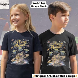 May include: Two youth t-shirts, navy and black, feature a "Pizza Planet" graphic. The design includes a rocket ship, aliens, and a pizza-planet-themed planet. The shirts have the text "Youth Tee Navy / Black" at the top.