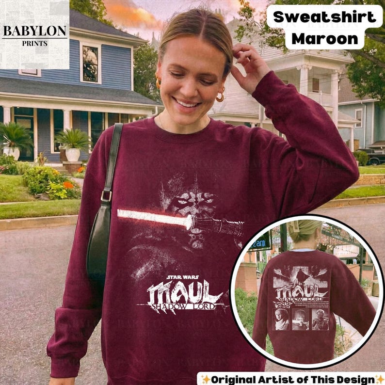 May include: Maroon sweatshirt featuring a Star Wars graphic of Darth Maul with a lightsaber. The text "STAR WARS MAUL SHADOW LORD" is below the graphic. The sweatshirt also has the text "Sweatshirt Maroon" on the top right.