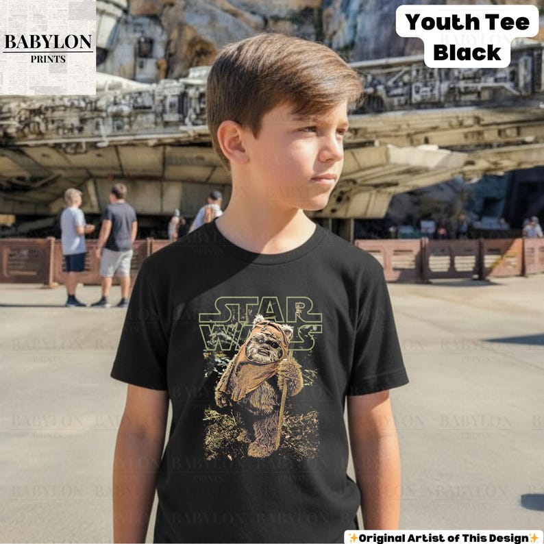 May include: Black youth tee featuring a Star Wars design with the text "STAR WARS" above an Ewok character holding a staff. The shirt also has the text "Youth Tee Black". The Babylon Prints logo is in the upper left corner.