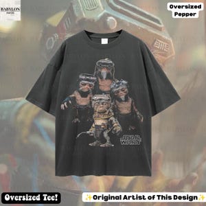 May include: A charcoal gray oversized t-shirt featuring a graphic print of four Babu Frik characters from Star Wars. The characters are depicted in a group, with one in the foreground holding a tool. The Star Wars logo is printed in white.