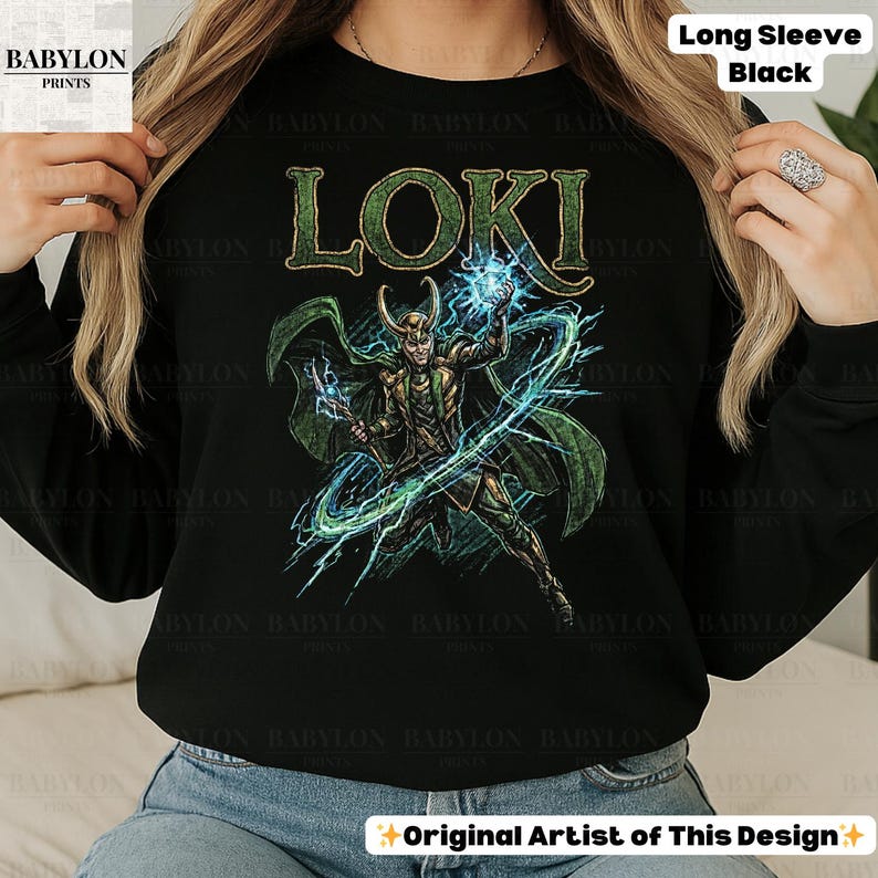 May include: Black long-sleeve shirt featuring a green and gold illustration of Loki with the word "LOKI" in green. The design includes lightning bolts and the text "Long Sleeve Black" at the top. The shirt has the text "Original Artist of This Design" at the bottom.