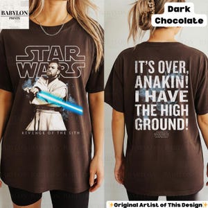 以下が含まれることがあります： ダークチョコレートブラウンのスターウォーズTシャツ。オビ＝ワン・ケノービと青いライトセーバー、テキスト「REVENGE OF THE SITH」が特徴。背面には「IT'S OVER, ANAKIN! I HAVE THE HIGH GROUND!」の引用句が表示されています。