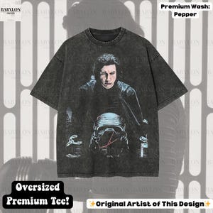 May include: Pepper-wash oversized premium tee featuring a graphic of a character from a science fiction film. The design includes a portrait and a helmet. The shirt has short sleeves and a crew neck. The text "Oversized Premium Tee!" is visible.